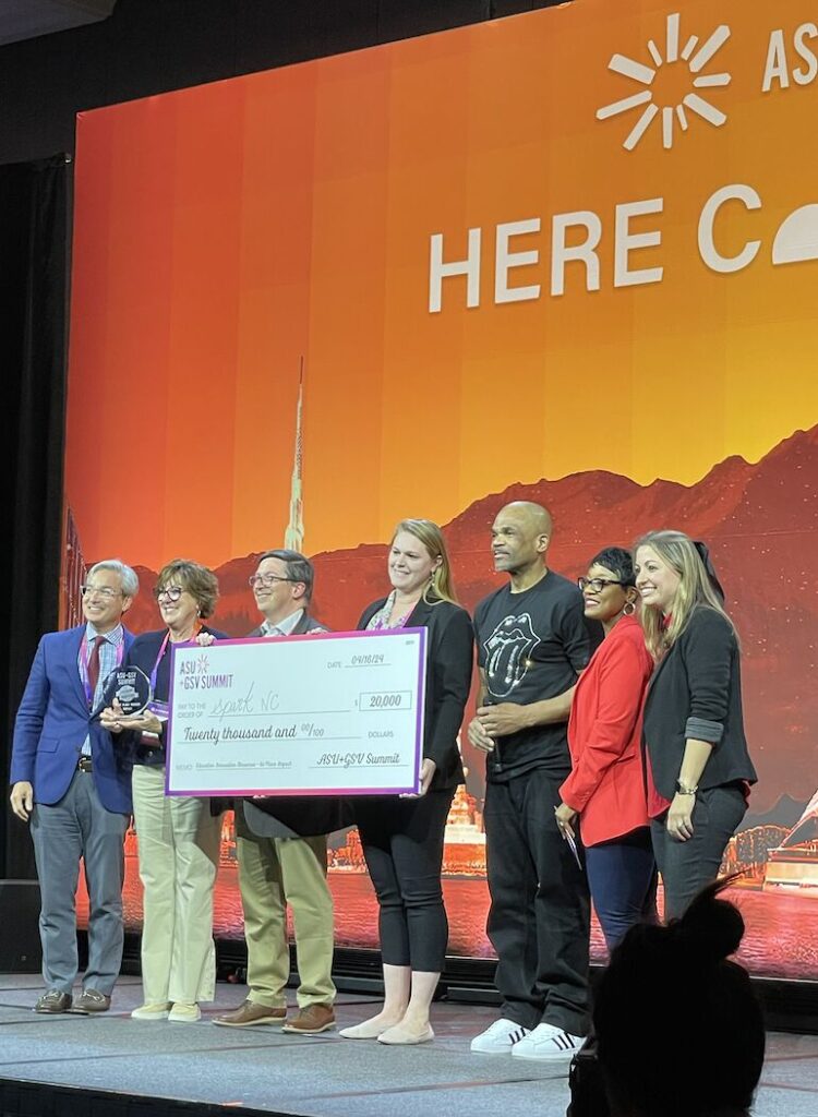 People on stage with a big check after winning an award.