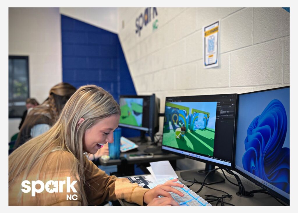 Student at computer with SparkNC logo